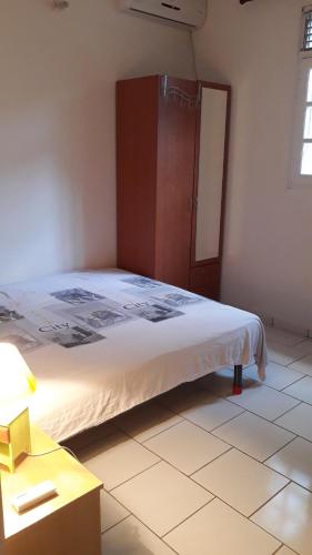 a bedroom with a large bed with a wooden cabinet at 1 à 3 chambres proche aéroport in Les Abymes