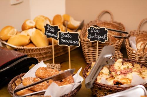 a table topped with baskets of pastries and baskets of bread at Hotel Cravo e Canela in Campos dos Goytacazes