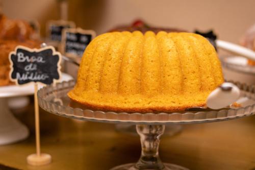 a yellow cake on a glass plate on a table at Hotel Cravo e Canela in Campos dos Goytacazes