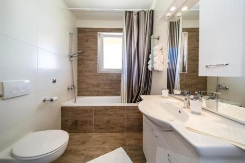a bathroom with a toilet and a sink and a tub at Apartments LeonDori in Krk