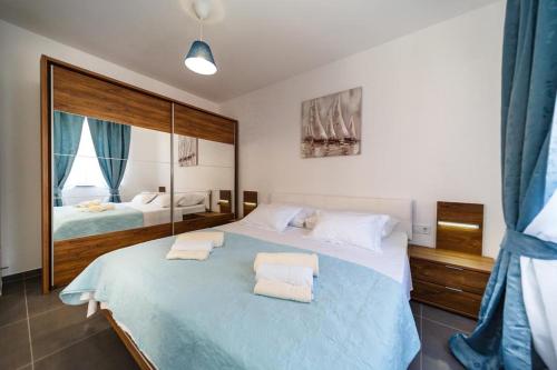 a bedroom with a large bed with two towels on it at Apartments LeonDori in Krk