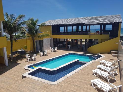 a house with a swimming pool and some chairs at Pousada Águas do Piruí in Arembepe