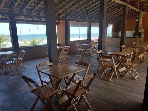 a restaurant with wooden tables and chairs and the ocean at Pousada Águas do Piruí in Arembepe