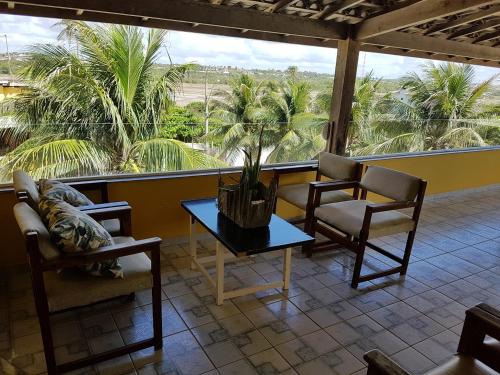 a room with two chairs and a table with a potted plant at Pousada Águas do Piruí in Arembepe