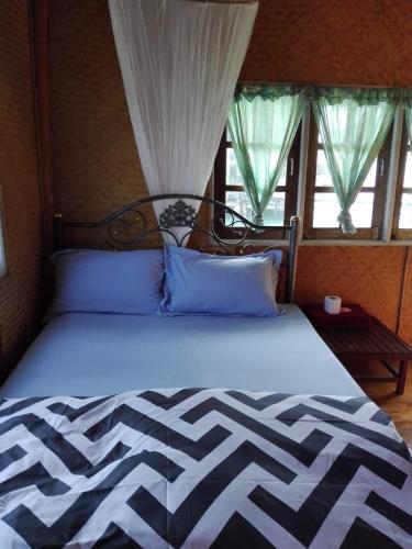 ein Bett mit blauen Kissen in einem Zimmer mit Fenstern in der Unterkunft Oceanblue Guesthouse in Ko Chang