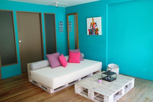 a room with a couch with pink pillows and a table at Meno Suites in Gili Meno