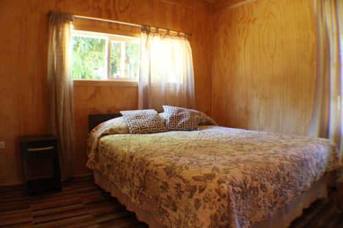 1 dormitorio con cama y ventana en Cabañas Ruta Del Lago, en Puerto Varas