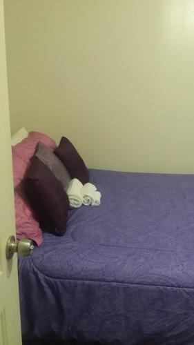 a bed with purple sheets and pillows on it at Dominique's Getaway NYC in Bronx