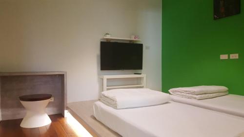a room with two beds and a flat screen tv at So Art Guesthouse in Sanyi