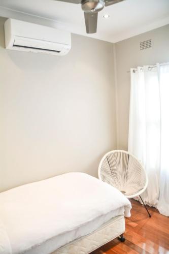 a bedroom with a white bed and a fan at Modern and Stylish 3 bedroom home, Western Sydney Ideal for Contractors in Colyton