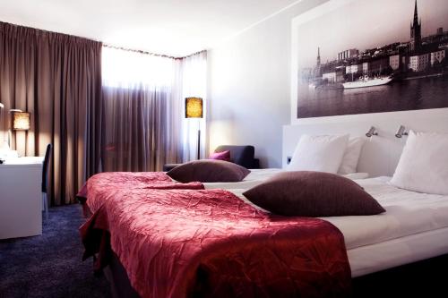 a hotel room with two beds with red sheets at Best Western Kom Hotel Stockholm in Stockholm