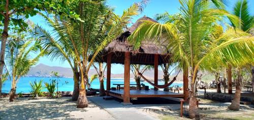 a pavilion on the beach with palm trees at Castaway Surf Retreat in Sekongkang