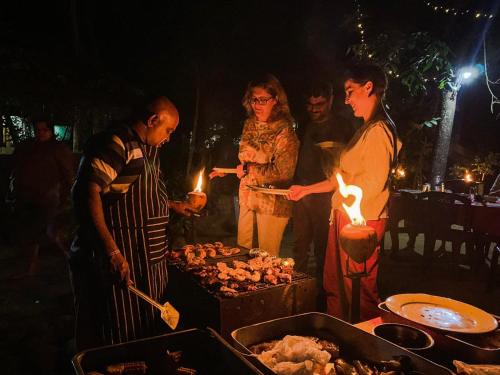 a group of people standing around a grill with lights at Dudley Nature Resort in Habarana