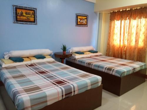 two beds in a room with blue walls at Mayon Lodging House in Legazpi