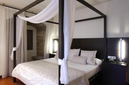 a bedroom with a canopy bed with white sheets and pillows at Hotel Palacio de Merás in Tineo
