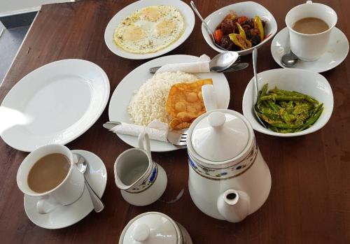 una mesa con platos de comida y tazas de café en Turtle Reef Guest, en Mirissa