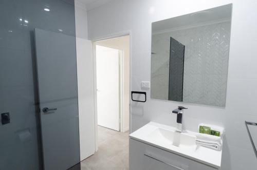 Baño blanco con lavabo y espejo en TiTree Village Holiday Apartments, en Port Douglas