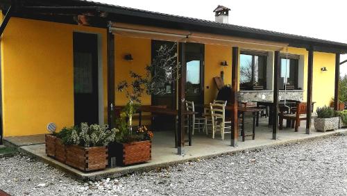 una pequeña casa amarilla con mesa y sillas en Agriturismo "La di Buiat, en Cividale del Friuli