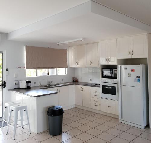 a kitchen with white cabinets and a white refrigerator at Blue horizon in Yeppoon