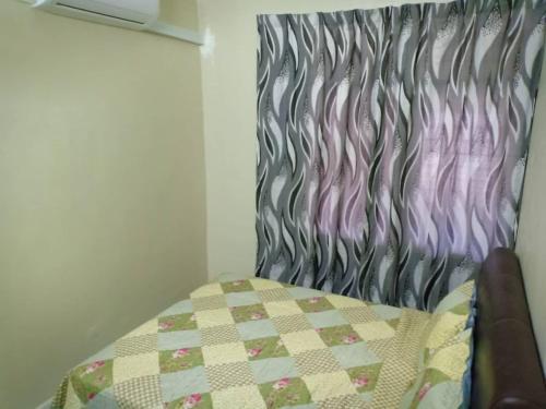 a bedroom with a bed with a quilt on it at Homestay Sejati in Kuala Berang