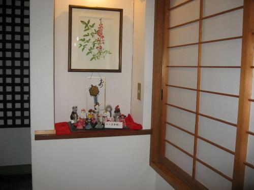a shelf next to a door with figurines on it at Ryokan Nakaya in Hamamatsu