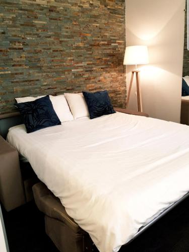 une chambre avec un grand lit blanc avec un mur de briques dans l'établissement Studio Cosy centre Cannes, à Cannes