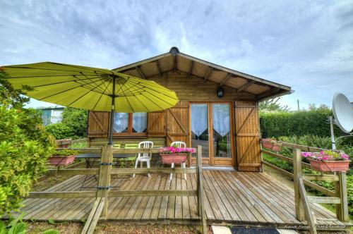 a wooden deck with a house with a yellow umbrella at Chalet in Plouër-sur-Rance