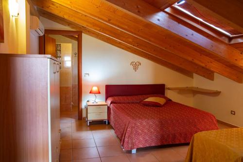 - une chambre mansardée avec un lit rouge dans l'établissement Agriturismo I Vigneti, à Olmedo