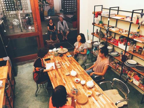 a group of people sitting around a wooden table at Yu Cafe Hostel in Songkhla