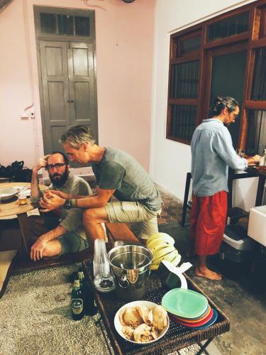 a group of men standing in a kitchen with a man sitting on a table at Yu Cafe Hostel in Songkhla