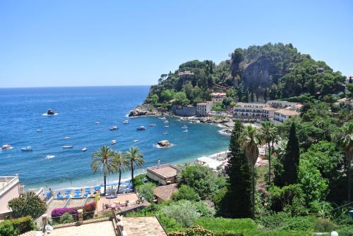 uma vista para uma praia com palmeiras e para o oceano em Hotel Baia Azzurra em Taormina