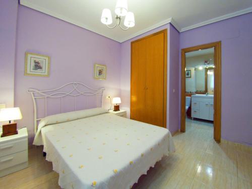 オロペサ・デル・マールにあるAPARTAMENTO EN MARINADOR FRENTE A LA PLAYAの紫の壁と白いベッドが備わるベッドルーム1室