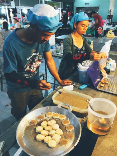 two people standing in a kitchen preparing food at Yu Cafe Hostel in Songkhla