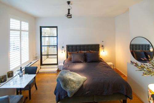 - une chambre avec un grand lit et un miroir dans l'établissement Zandvoort Studio, à Zandvoort