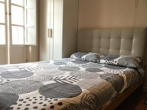 a bed with a black and white comforter and a window at Vidrio Apartment in Seville