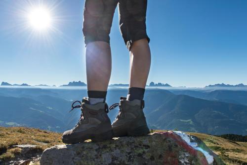 a person standing on top of a mountain wearing hiking boots at Boutique Pension Erlacher - Adults Only in Villandro