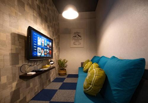 a living room with a blue couch and a flat screen tv at Vibrant Hostel in Kota Kinabalu
