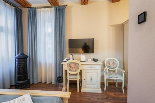 a room with a desk with two chairs and a tv at HOTEL BOUTIQUE CASA CHITIC -HOTEL AND RESTAURANT Str Johann Gott nr7 in Braşov