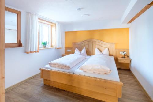 a bedroom with a bed with a wooden headboard and a window at Gästehaus Schlegel in Gunzesried