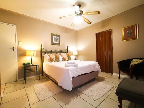 a bedroom with a bed and a ceiling fan at Loerie Guesthouse in Hoedspruit