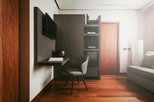 a room with a chair and a desk with a television at Bacã Suites, Restaurant & Bar in Taranto