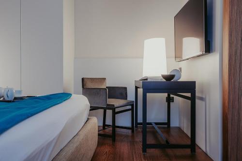 a bedroom with a desk and a bed and a table and chair at Bacã Suites, Restaurant & Bar in Taranto
