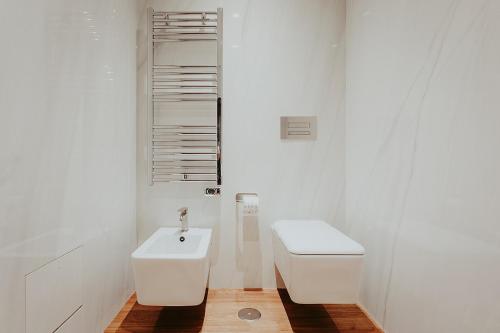 a white bathroom with a toilet and a sink at Bacã Suites, Restaurant & Bar in Taranto