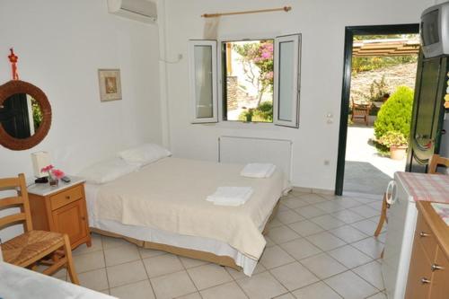 a white bedroom with a bed and a window at Handakas Studios in Andros