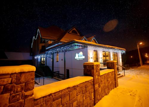 a building covered in christmas lights in the snow at GORHouse Hotel in Yaremche