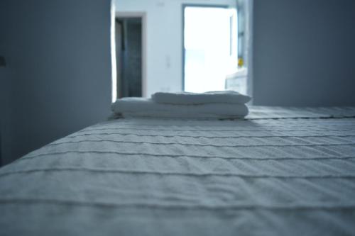Una cama blanca con dos almohadas encima. en Sopravento House, en Serifos Chora