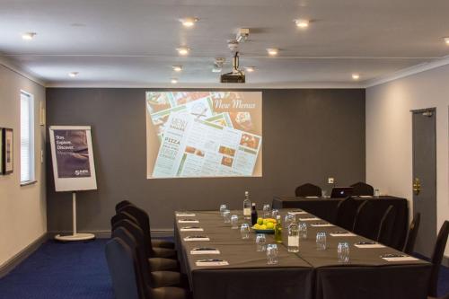 a conference room with a long table with chairs and a screen at Dragonfly Hotel King's Lynn in Kings Lynn
