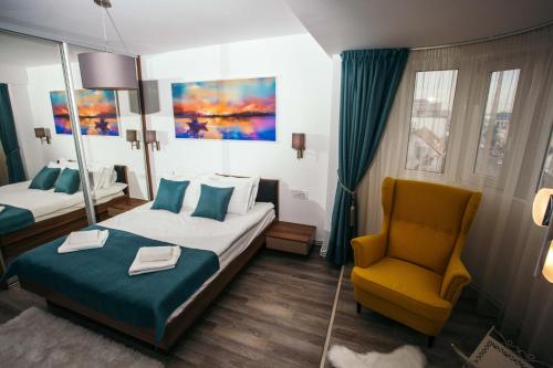 a hotel room with a bed and a yellow chair at Briana Luxury Apartment in Cluj-Napoca