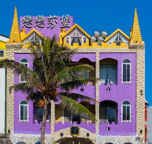 a purple building with a palm tree in front of it at 墾丁戀戀莎堡特色民宿 Castillo in Eluan