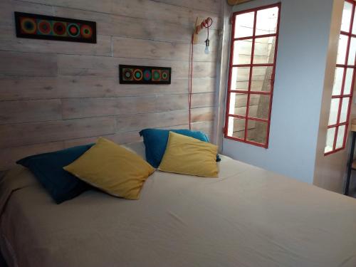 a bedroom with a white bed with blue and yellow pillows at El Tamarisco in Puerto Pirámides